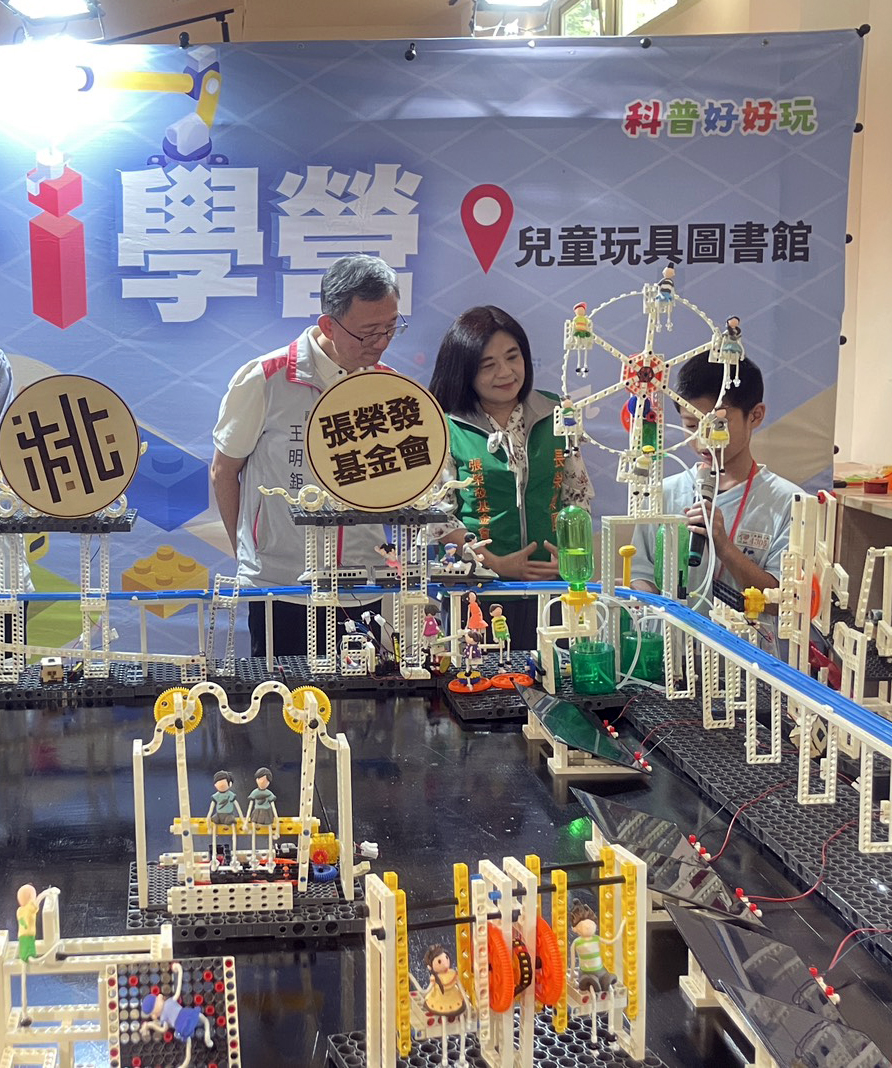 張榮發基金會攜手桃園市政府推出「科普好好玩」專案，今於桃園兒童玩具圖書館舉辦科普小桃子Ｉ學營，由學生向桃園市副市長王明鉅(左1)與張榮發基金會執行長鍾德美(中)說明微型積木拼組巧思。