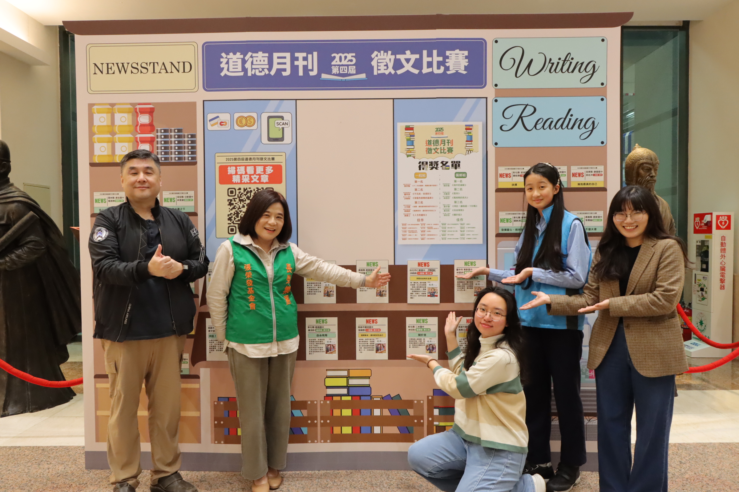 仁愛國中洪桐桐同學在〈深藍色座椅的溫柔〉作品小卡上簽名，與鍾德美執行長（左二），及全班師生分享這份喜悅。