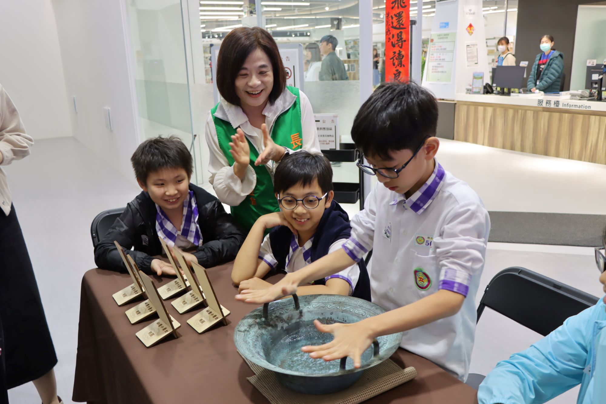 張榮發基金會執行長鍾德美（中著綠背心）與慈文國小學生一起進行龍洗盆水波紋實驗。