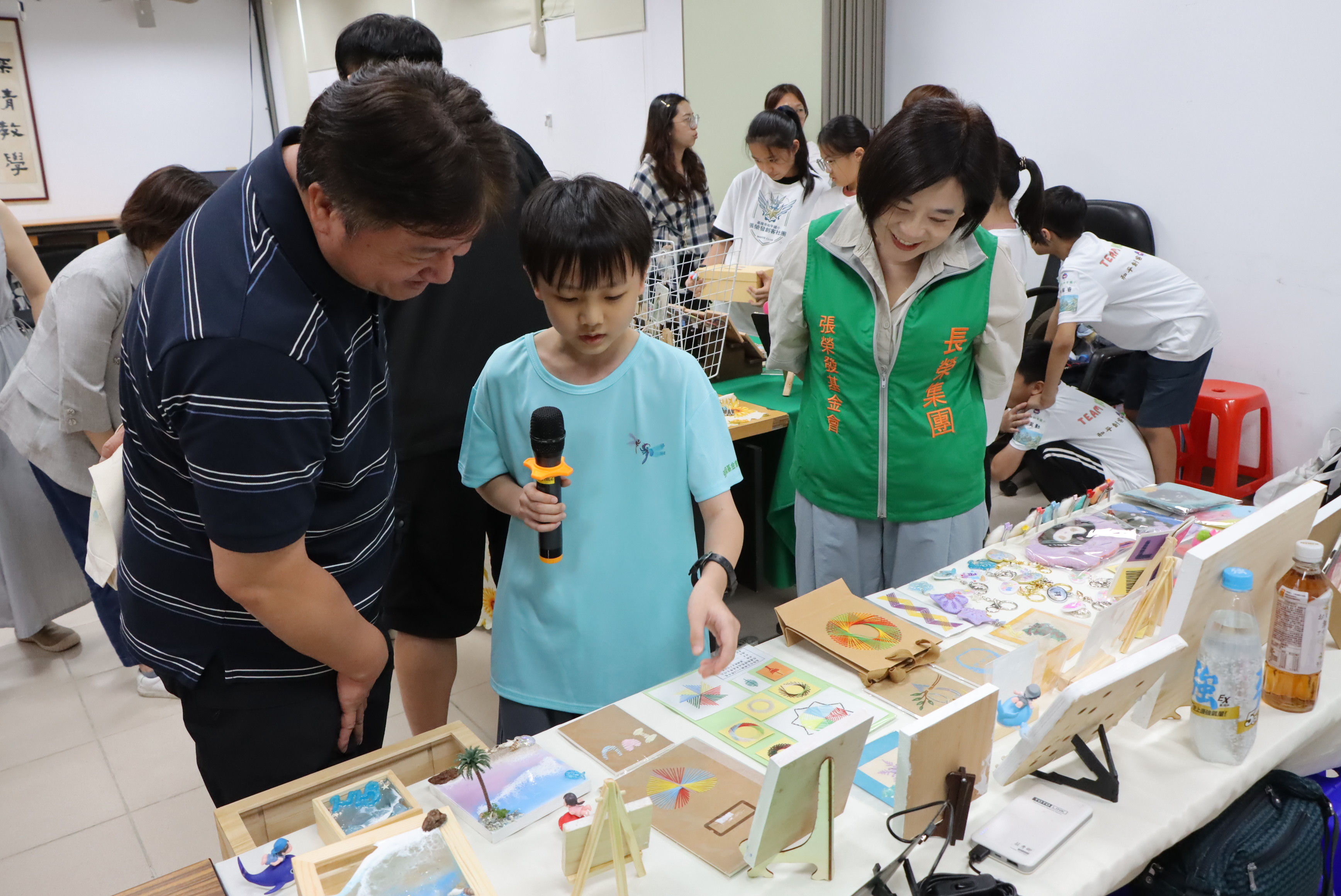 張榮發基金會執行長鍾德美(右一)與基隆市教育處課程教學科課程督學巫建男(左一)聆聽長樂國小學生說明創客作品設計過程。