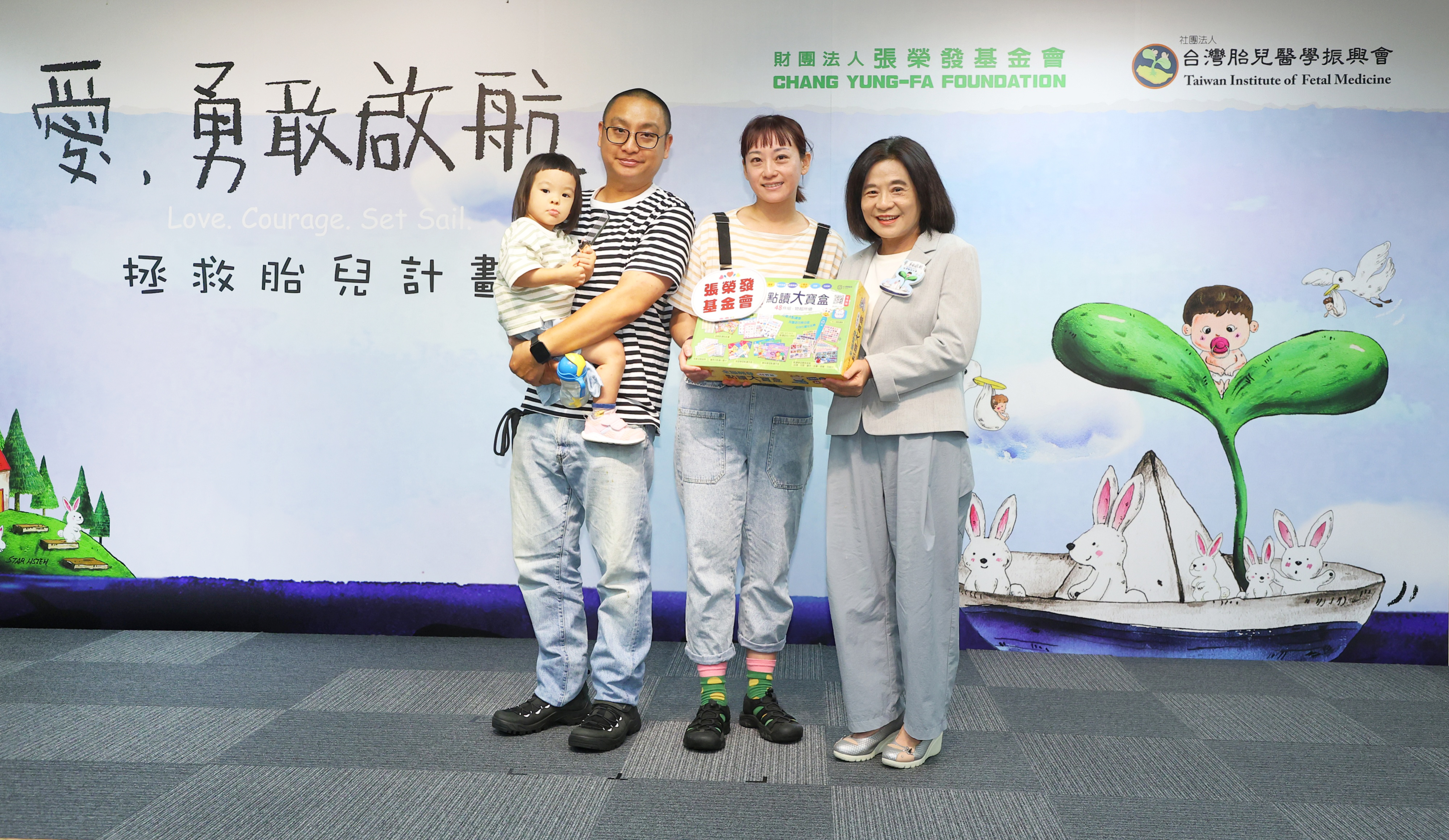 張榮發基金會鍾德美執行長（右一）致贈「全腦開發點讀大寶盒」給田心小妹妹、田爸爸、田媽媽（左一至左三）傳遞對唇顎裂寶寶及家庭的關懷與支持。